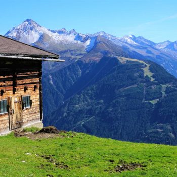 Holzhütte auf einer Wiese in den Alpen mit Blick auf Bergkette