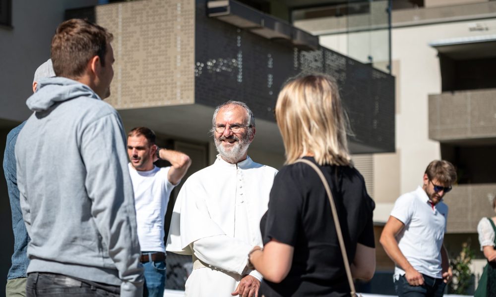 Pfarrer Christoph Pernter im Gespräch mit Gästen der Fertigstellungsfeier beim ZIMA Projekt Brandjochblick in Völs